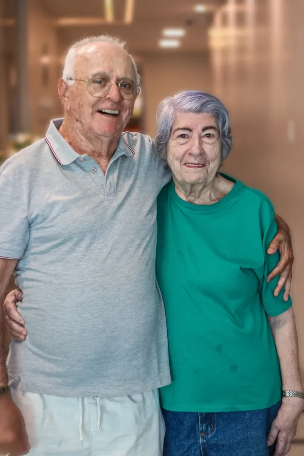 Suzana abraçada a um senhor da família, os dois sorrindo