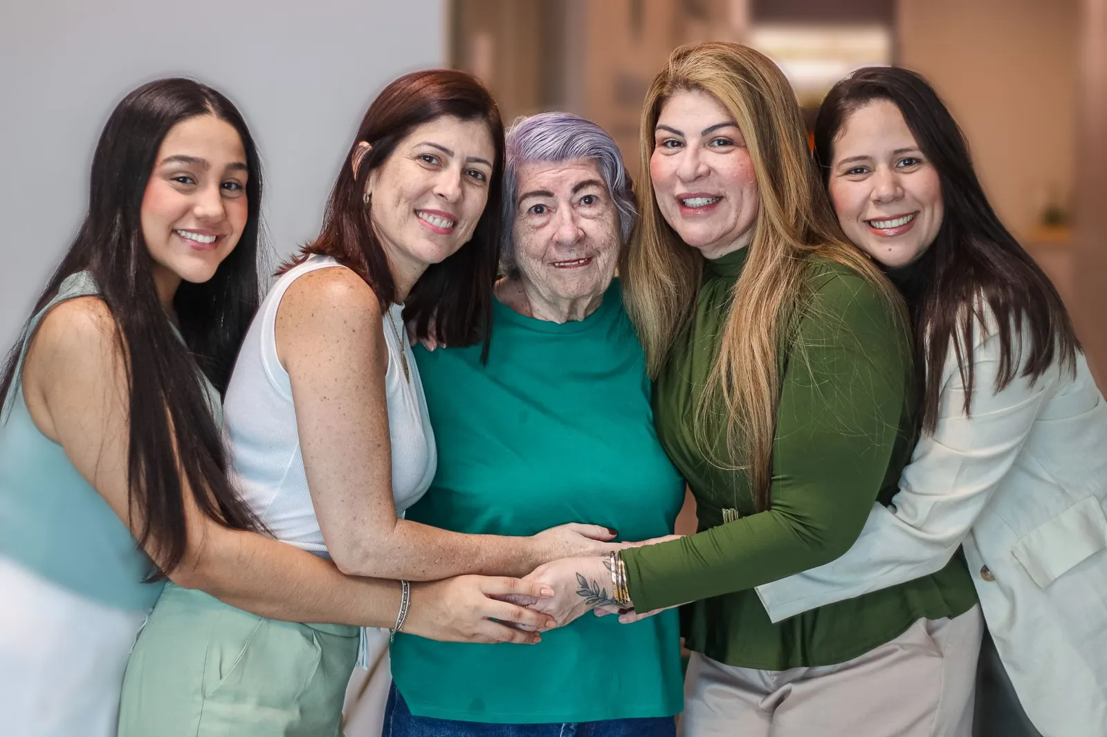 Suzana, a bisa de cabelos lilás, abraçada por Analice, Alice e as mulheres da família