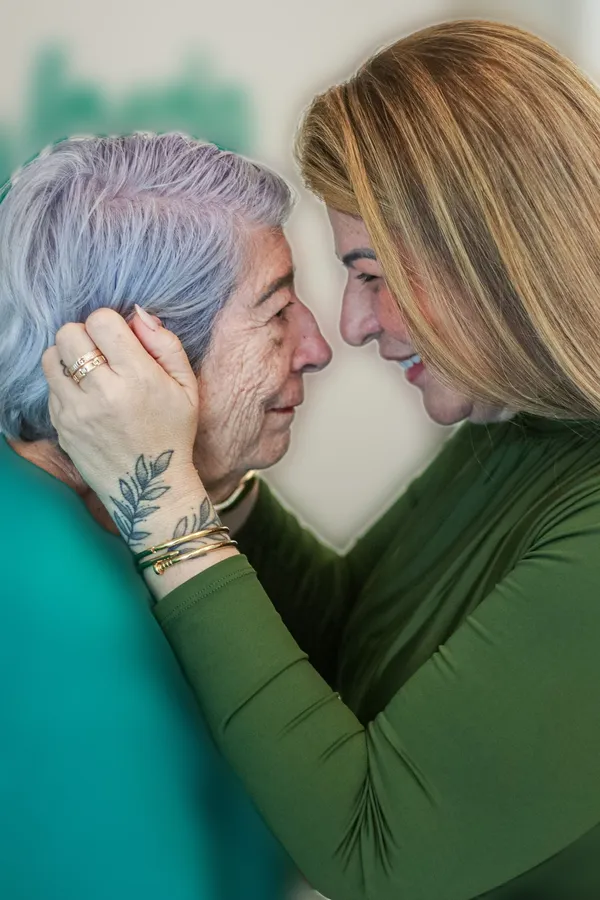 Analice e a mãe, Suzana, encostam a testa, de olhos fechados